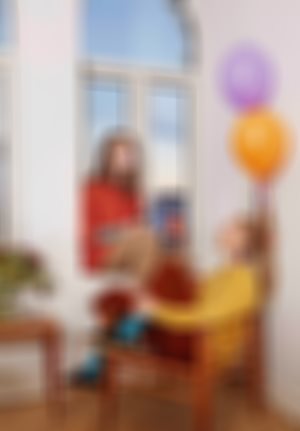 En ung dame sitter i vinduskarmen. En ung dame sitter i en stol. Bak dem er det noen ballonger.