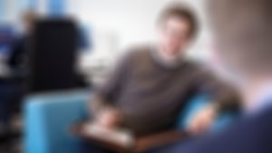 Rådgiver i Sparebanken Møre sitter på sofa og smiler imøtekommende til deg.